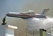 Russian Beriev BE-200 fire-fighting plane operating on mountain fire very close to houses