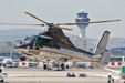 A helicopter about to land in Athens airport helipad with the control tower in the background